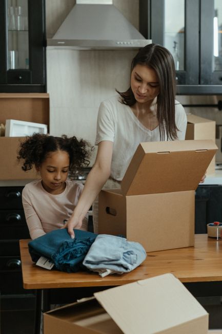 A mother and daughter unpacking boxes in their kitchen during a move to a new home.